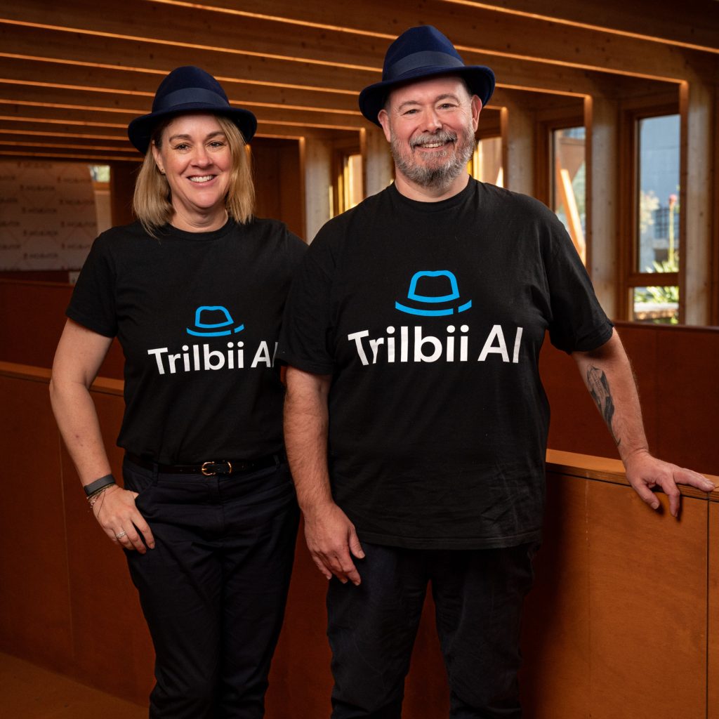 Trilbii AI co-founders Carolyn S Dean and Anthony Middlemiss wearing Trilbii AI shirts and navy trilby hats